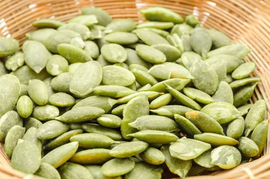 Dried Pumpkin Seeds in weave basket on white background.