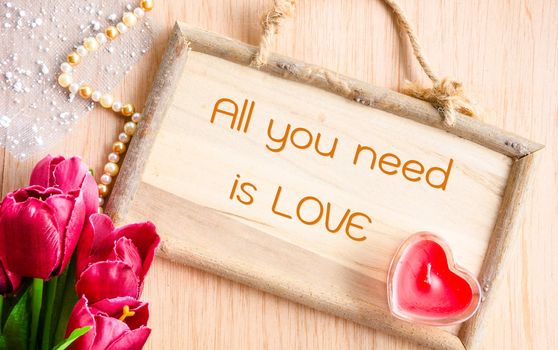 All you need is love. Clock and red tulip with red candle heart shape on wooden background.