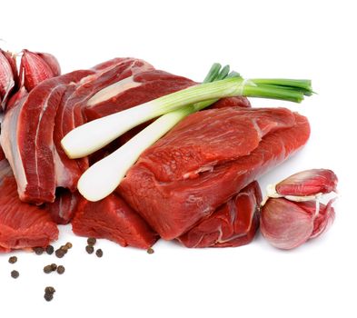 Pieces of Boneless Raw Beef with Spring Onion, Garlic and Pepper Corn isolated on White background