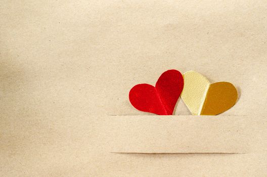 Gold heart and red heart on vintage brown paper background with copy space.