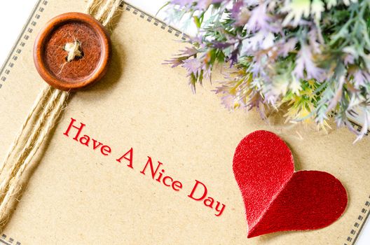 Have a nice day on brown taheart and red paper with leaf on whtie background.