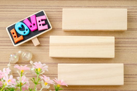 LOVE wording and blank wooden tag with flower on wooden background.