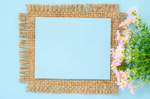 Blue paper blank tag with flower on sack background for your text.