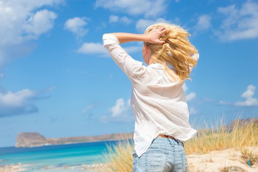 Relaxed woman enjoying freedom and life an a beautiful sandy beach.  Young lady feeling free, relaxed and happy. Concept of freedom, happiness, enjoyment and well being.  Enjoying Sun on Vacations.