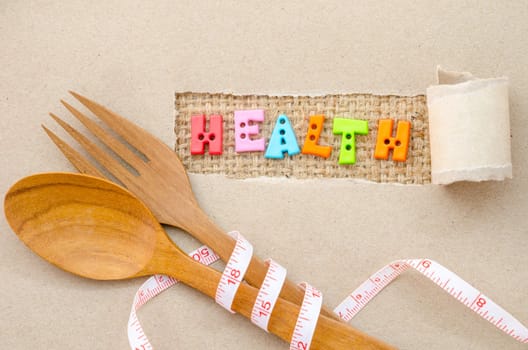 Health alphabet and wooden fork and spoon with Measure on brown paper background. Diet for healthy concept.