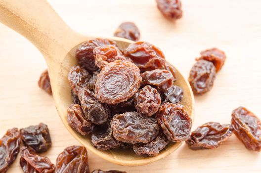 Raisin in wooden spoon on wooden background.