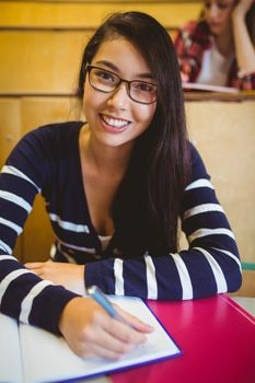 Smiling student writing on notebook at the university