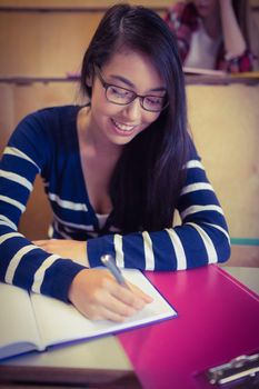 Smiling student writing on notebook at the university