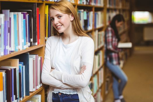 Smiling student leaning against bookshelves at the university