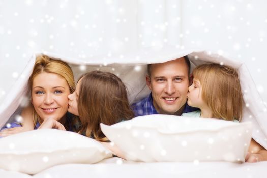 family, children, comfort, bedding and home concept - happy family with two kids under blanket over snowflakes background