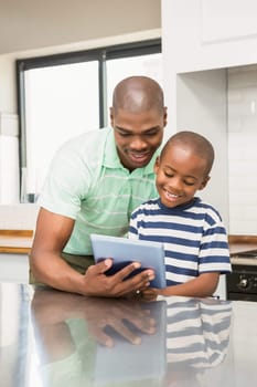 Father using tablet with his son in the kitchen
