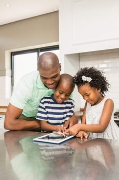 Father using tablet with his children in kitchen at home