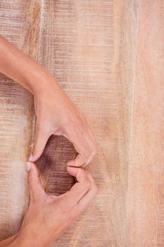 View of hands making heart shape on wooden desk