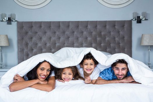 Happy family under the blanket posing for camera