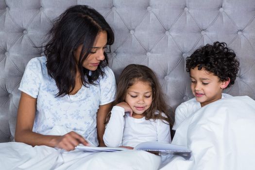 Happy family reading book on the bed at home