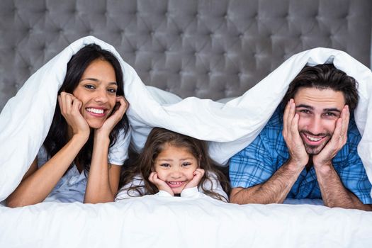 Happy family under the blanket posing for camera