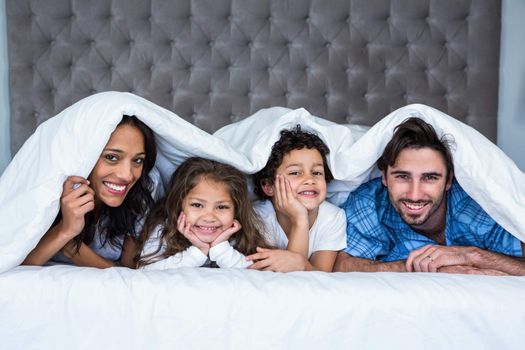 Happy family under the blanket posing for camera