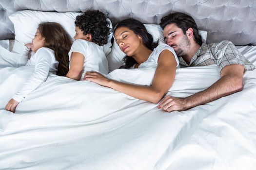 Family sleeping together in bed 