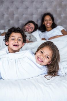 Happy family in bed with children in foreground