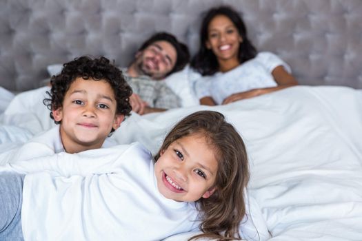 Family in bed with children in foreground 