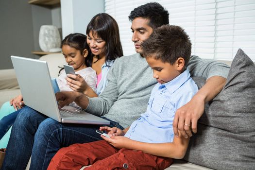 Family sitting on the sofa and using technology