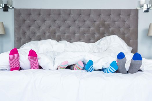 Family feet with socks sticking out from the blanket