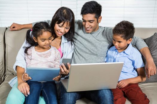 Smiling family on the sofa using technology