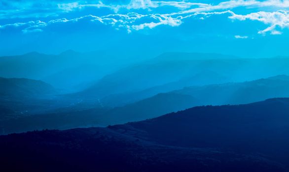mountain silhouette with fog, natural light tint blue