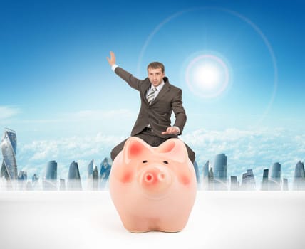 Businessman sitting on piggy bank on nature background