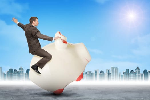 Businessman sitting on piggy bank on nature background