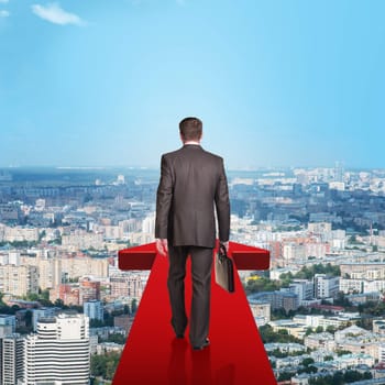 Businessman on red arrow above city, rear view