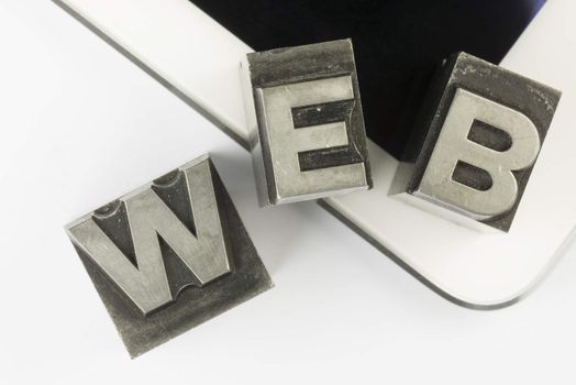 Old lead ink printing type letters from a book printing company, as a collage positioned on a modern tablet.
