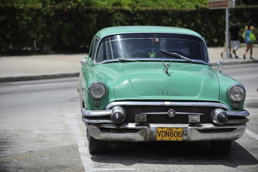 Old Havana, Cuba, -  August  2013. The old vintage-styled car in the historical center of Havana is waiting for the tourists to board. Riding an auto of the 20's - 50's is one of the attractions for the tourists in Cuba. Such cars are used for any goal, not only tourism, but taxis and personal needs.