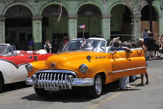 Old Havana, Cuba, -  August  2013. The old vintage-styled car in the historical center of Havana is waiting for the tourists to board. Riding an auto of the 20's - 50's is one of the attractions for the tourists in Cuba. Such cars are used for any goal, not only tourism, but taxis and personal needs.