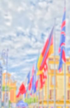 Defocused background with flags of European Countries against a cloudy sky. Intentionally blurred post production for bokeh effect