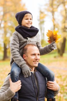 family, childhood, season and people concept - happy father and son having fun in autumn park