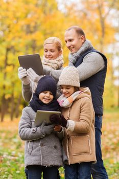 family, childhood, season, technology and people concept - happy family with tablet pc computers in autumn park