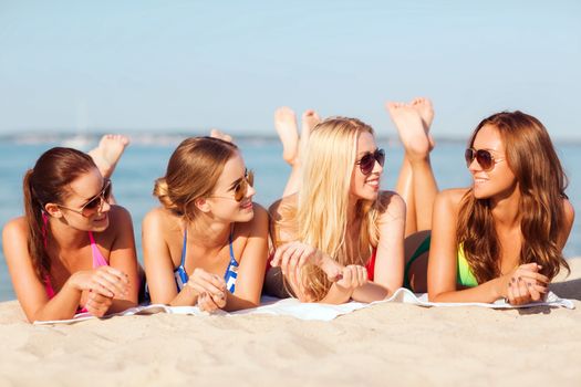 summer vacation, holidays, travel and people concept - group of smiling young women in sunglasses lying on beach