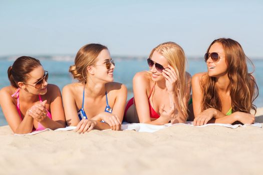 summer vacation, holidays, travel and people concept - group of smiling young women in sunglasses lying on beach