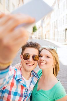 travel, vacation, technology and friendship concept - smiling couple with smartphone in city