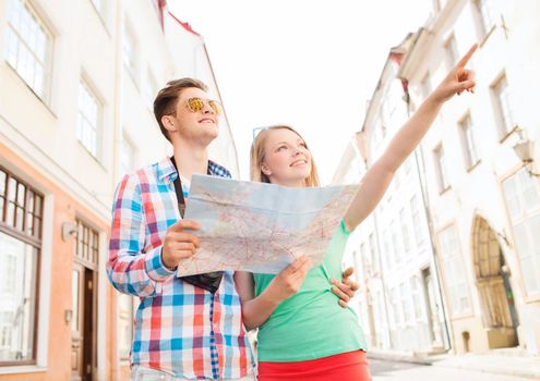 travel, vacation, technology and friendship concept - smiling couple with map and photo camera exploring city