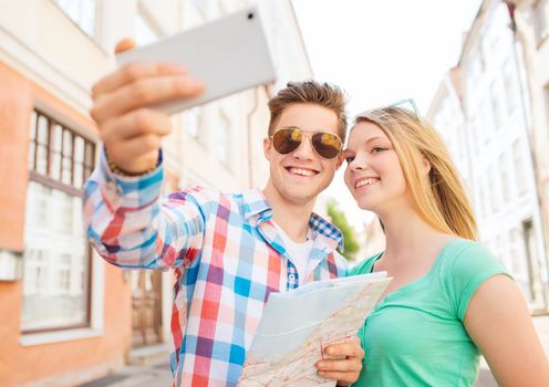 travel, vacation, technology and friendship concept - smiling couple with smartphone in city