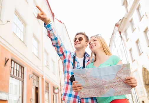 travel, vacation, technology and friendship concept - smiling couple with map and photo camera exploring city