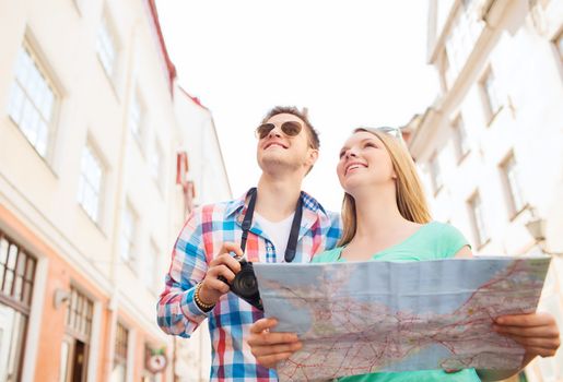 travel, vacation, technology and friendship concept - smiling couple with map and photo camera exploring city