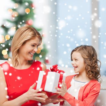 christmas, holidays, people and family concept - smiling mother and daughter with gift box at home