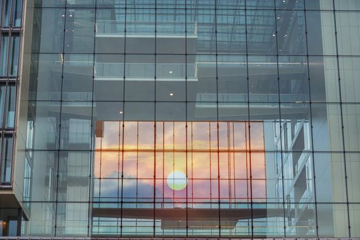 Modern blue glass wall of an office building in the background a sunset.
