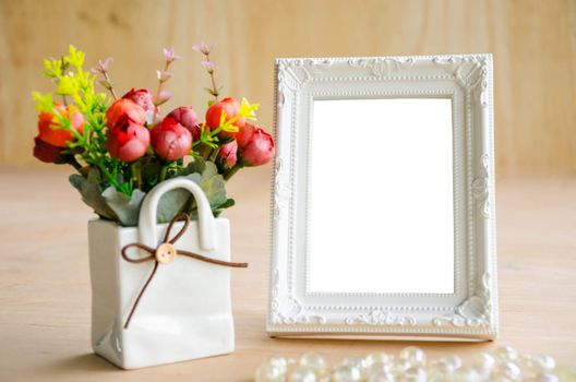 Blank vintage photo fame and flower on wooden background. Save with clipping path.