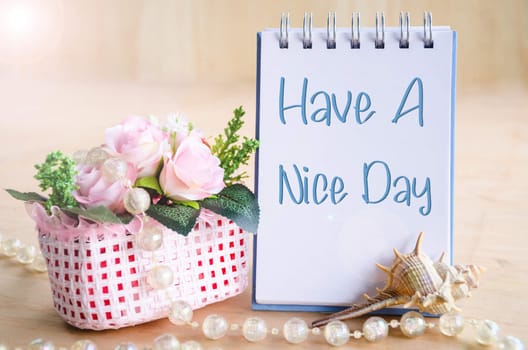 Have a nice day. On diary with flower cup on wooden background.