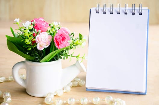 Open blank diary and flower on wooden background.