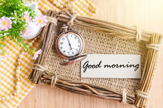 Good morning text in sack photo frame with flower on wooden background.
